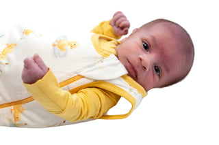 Newborn baby wearing a yellow and white bamboo sleep sack  on a white background