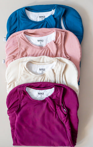 Stack of folded shirts in blue, pink, white, and purple on a light background