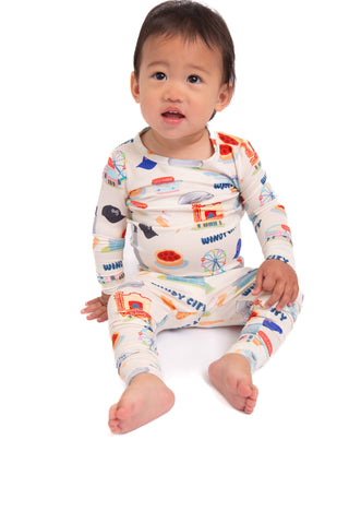 Baby wearing a colorful long-sleeve shirt with vehicle pattern on a white background