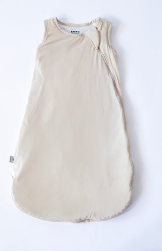 Beige baby sleeping bag with a bow on a white background