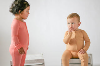 Two children wearing pink and beige outfits on a white background