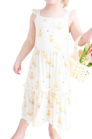 Child wearing a white dress with yellow floral patterns, holding a basket of flowers.