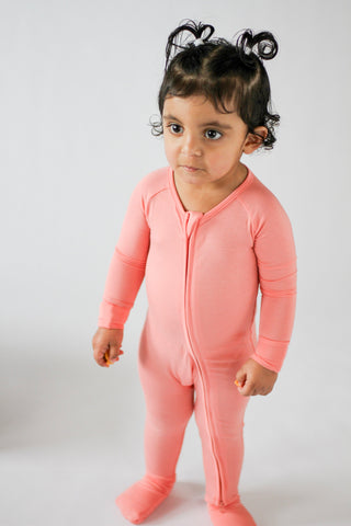 Child wearing a pink onesie against a white background
